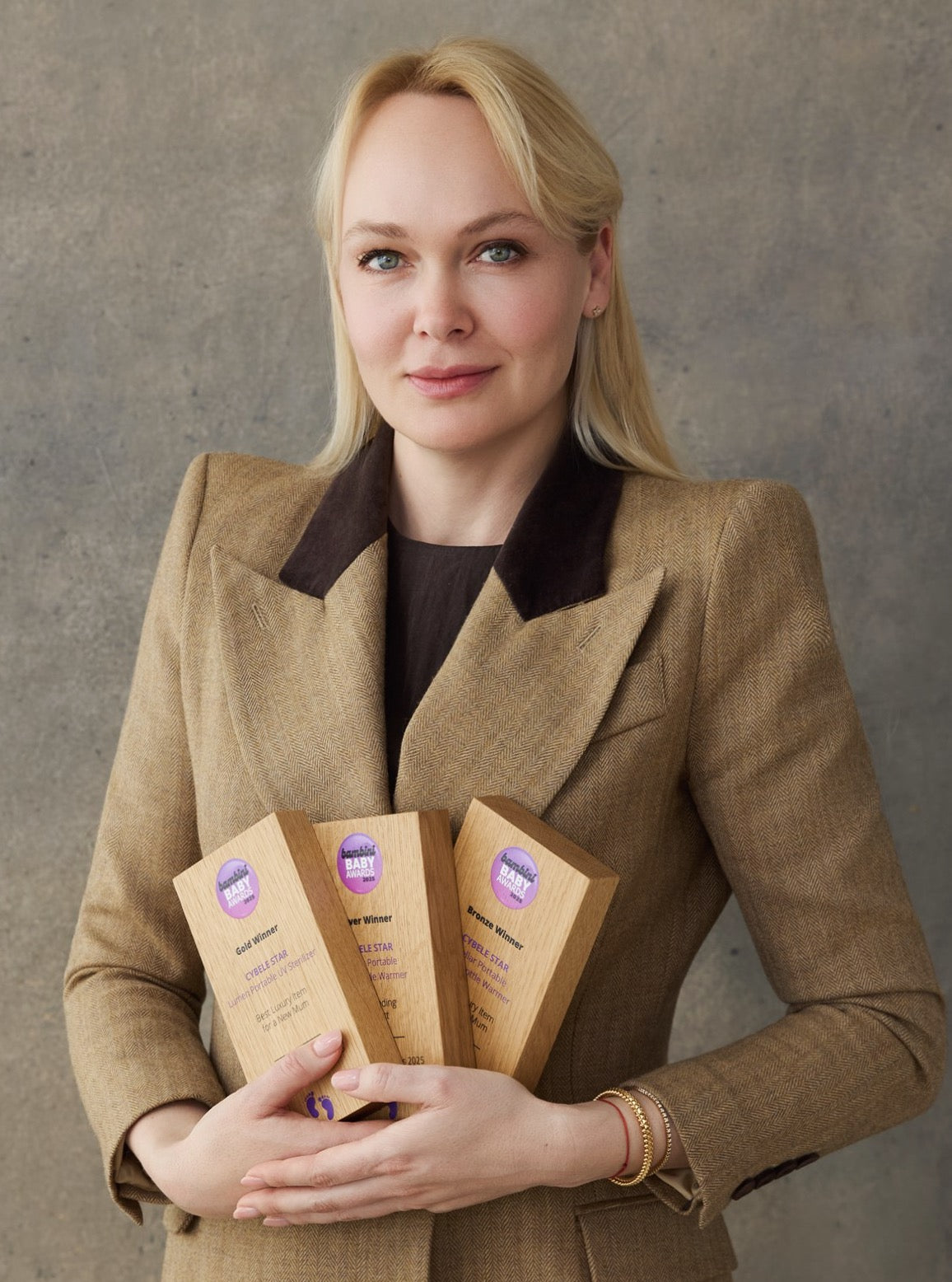 Kristina Lileeva, CEO and founder of Cybele Star, with Bambini Baby Awards 2025 trophies (Gold, Silver and Bronze) for award-winning baby care products.