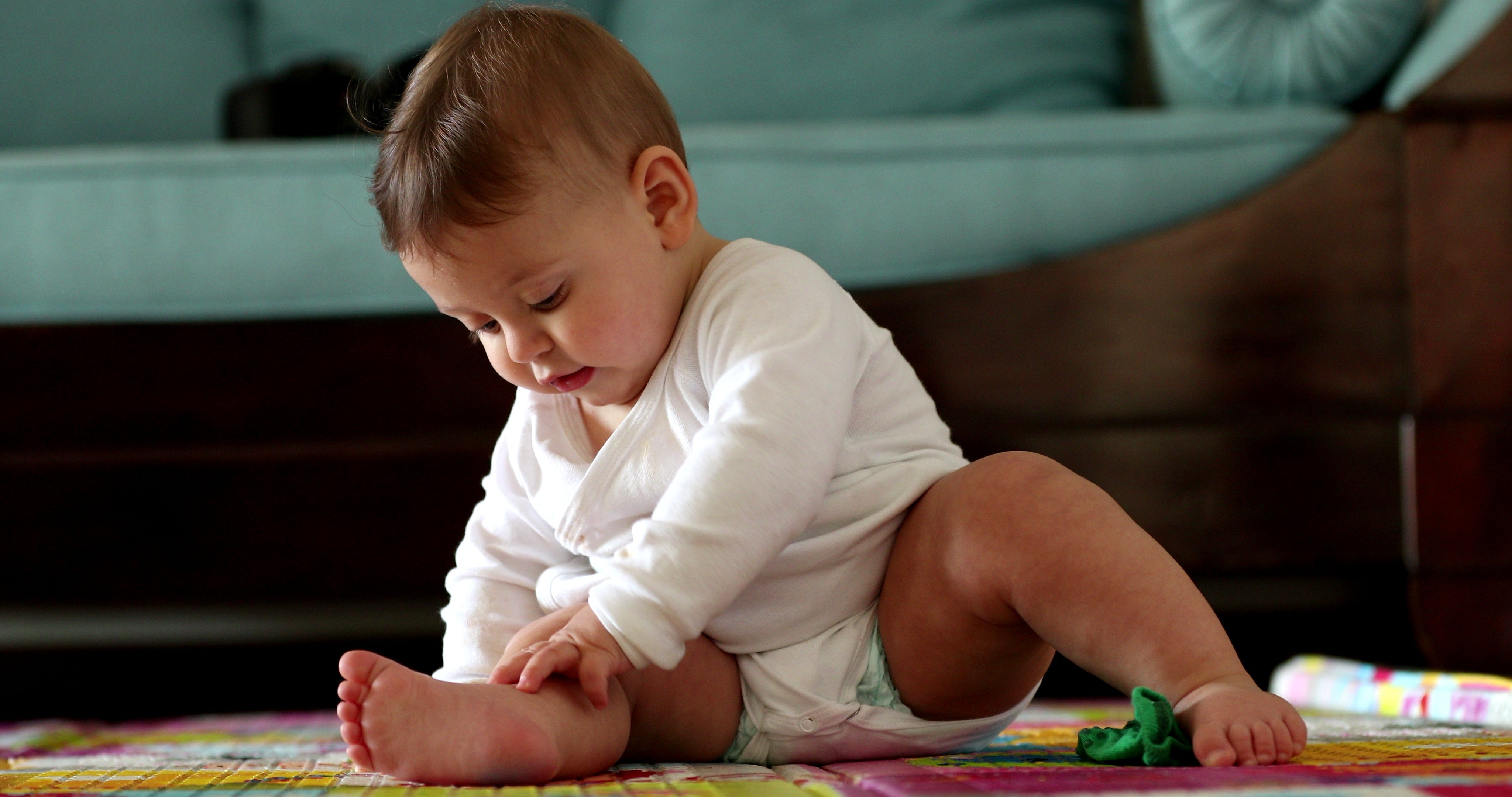 An image of a baby playing on the floor of a living room. 
